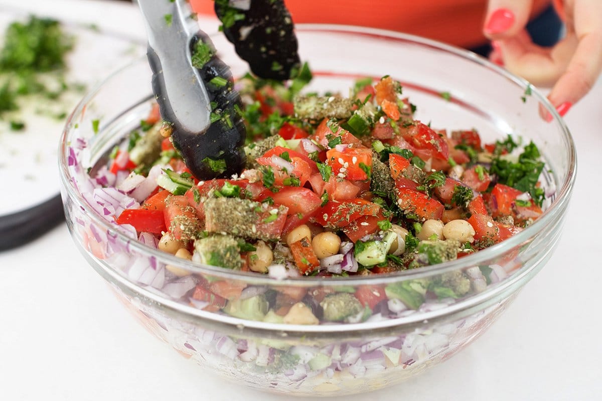 Tossing lebanese chickpea salad in a bowl