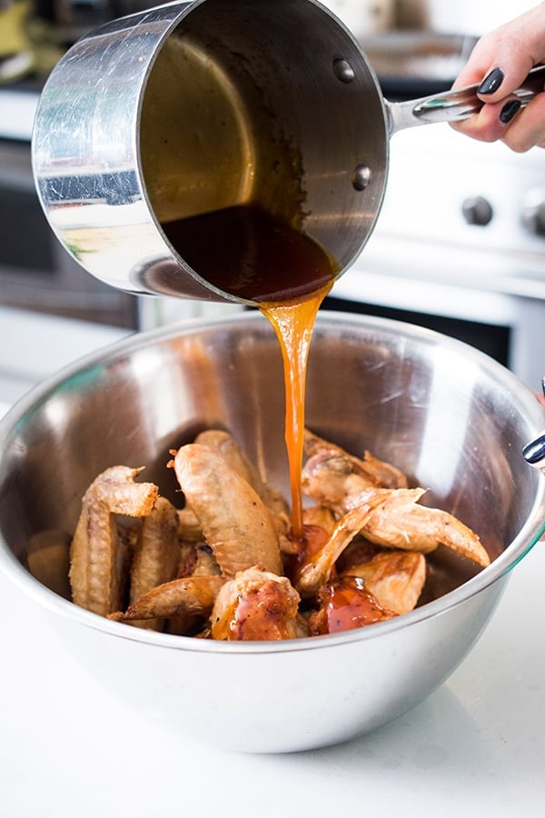 honey being added to a bowl of chicken wings