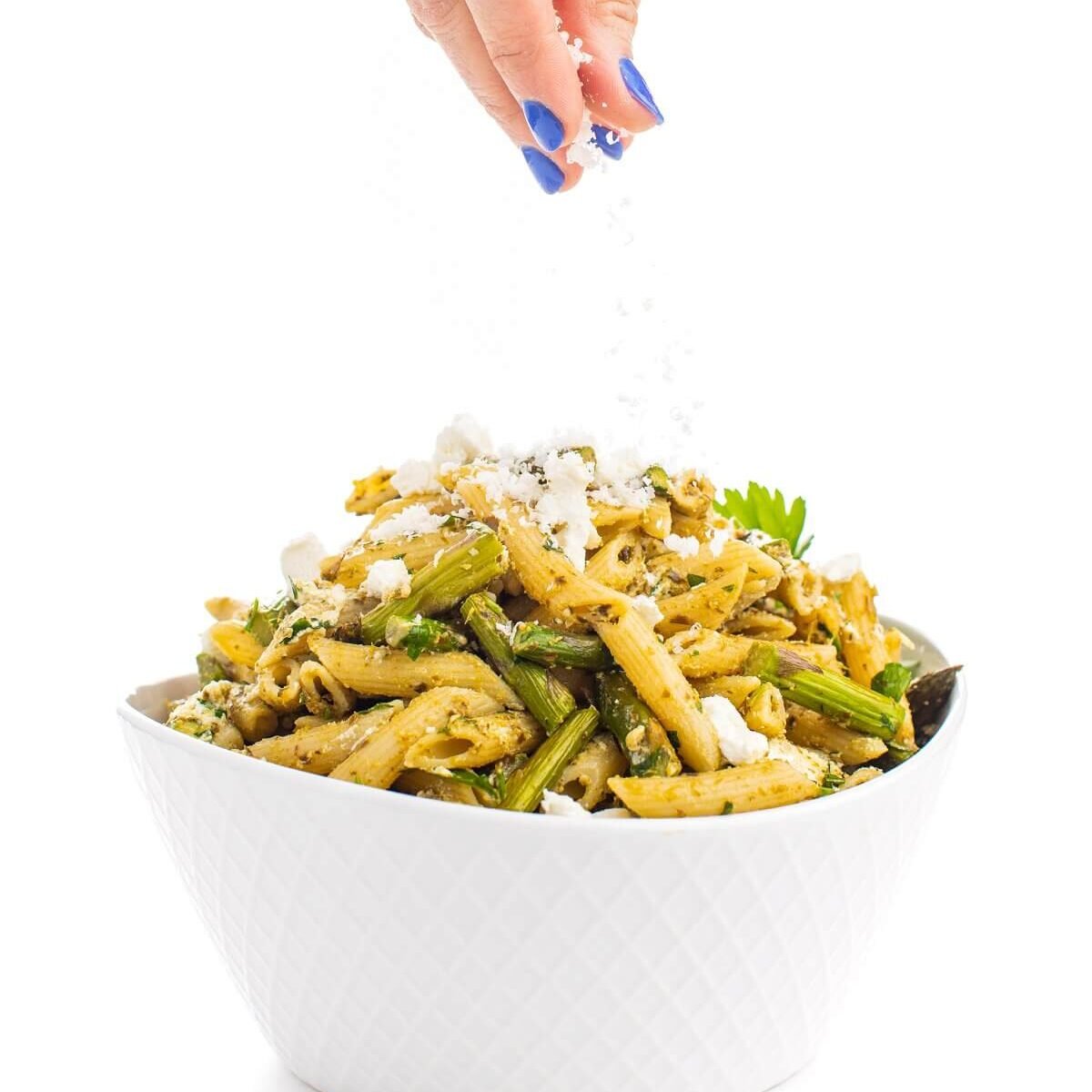 Pesto Pasta with Asparagus and Goat Cheese being sprinked into a bowl