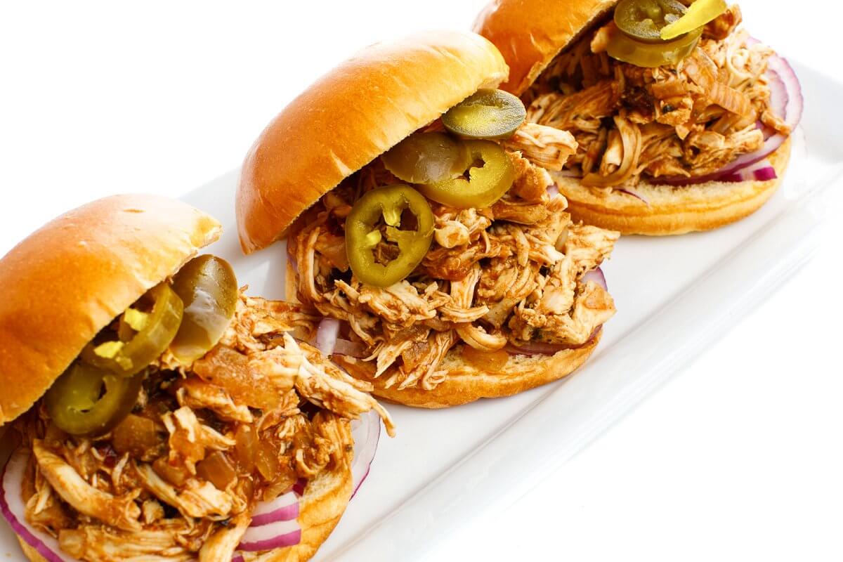 A plate of three sandwiches with BBQ chicken
