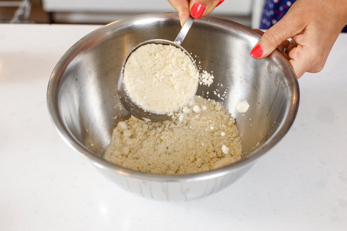 Pouring almond flour into metal bowl.