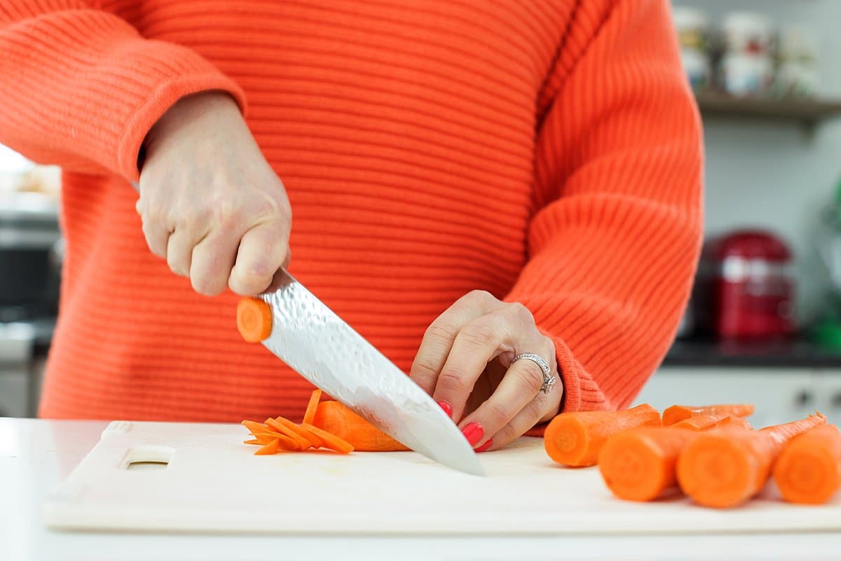 Liz cutting carrots on a cutting board.