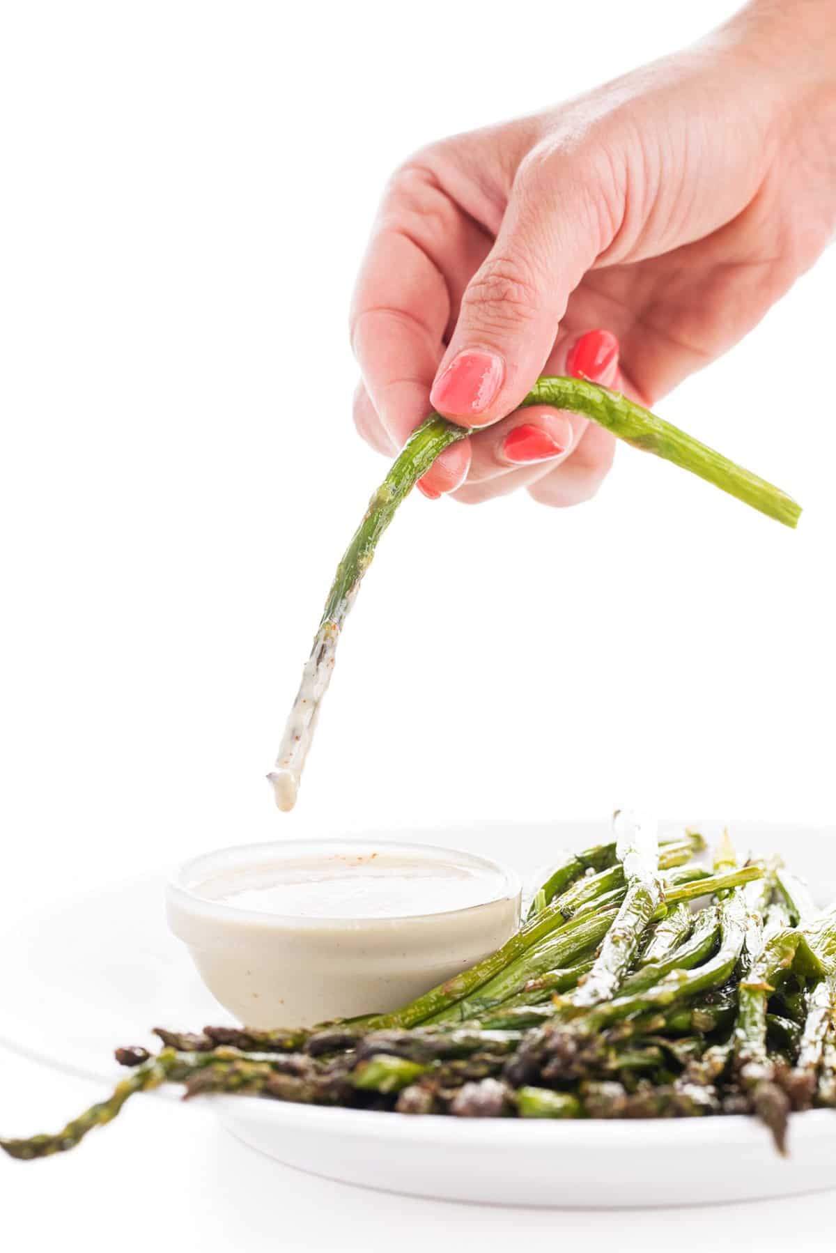 Liz dipping broiled asparagus into tahini sauce
