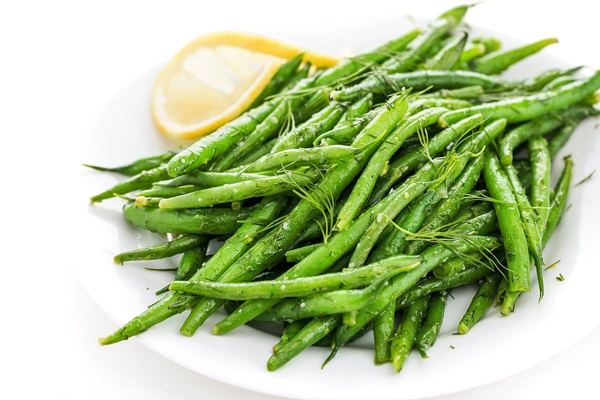 Lemon Dill green beans on a plate with a slice of lemon, another healthier Thanksgiving side dish.