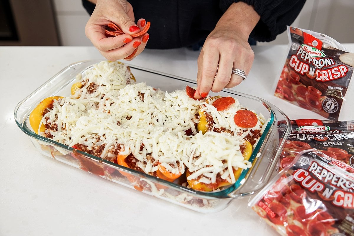 adding pepperoni on top of pizza stuffed peppers