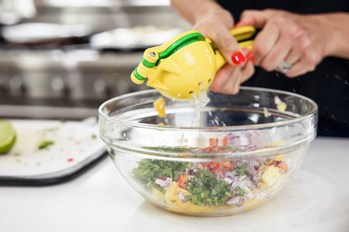 Squeezing fresh lime juice into mango salsa.