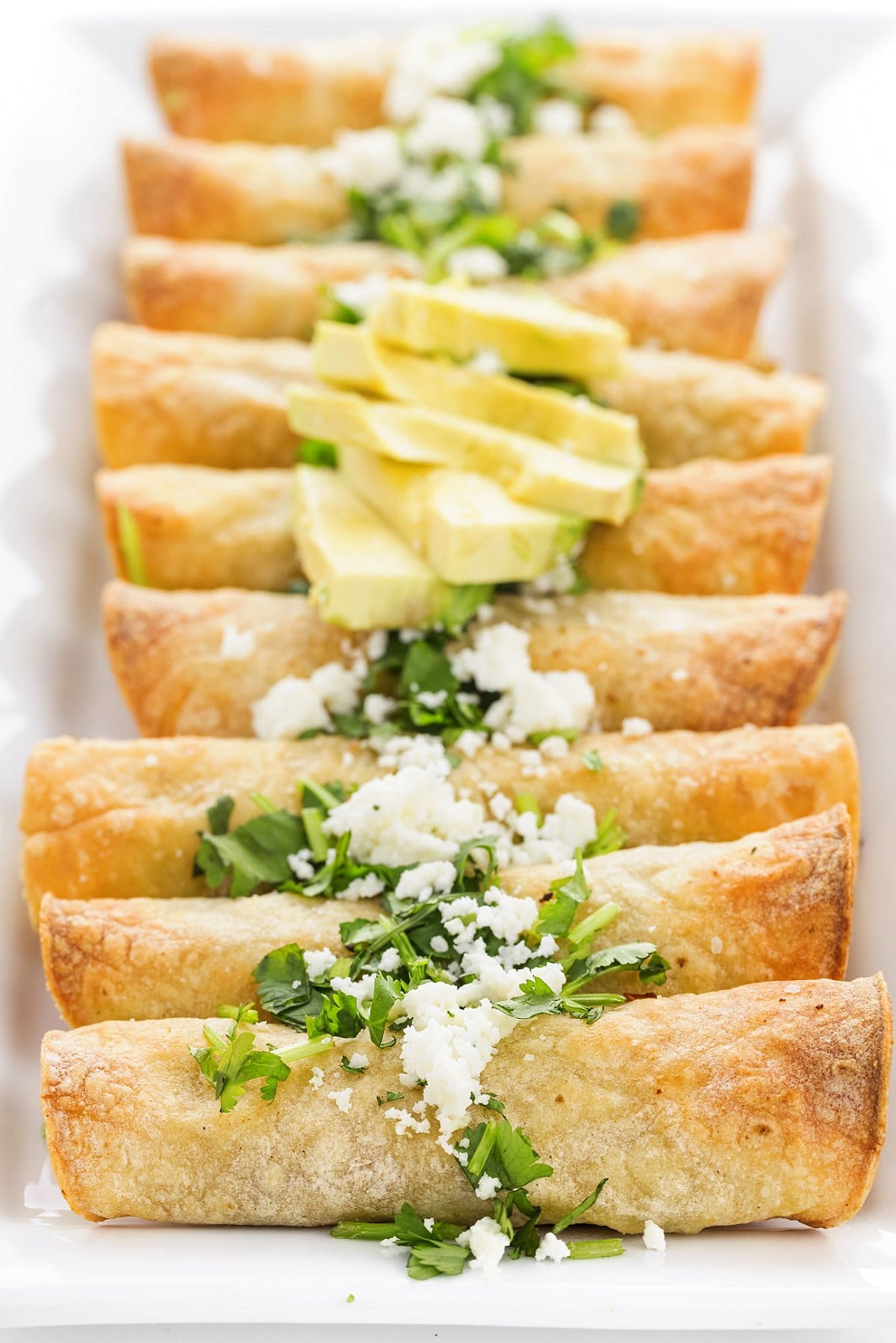 row of baked chicken taquitos on a plate