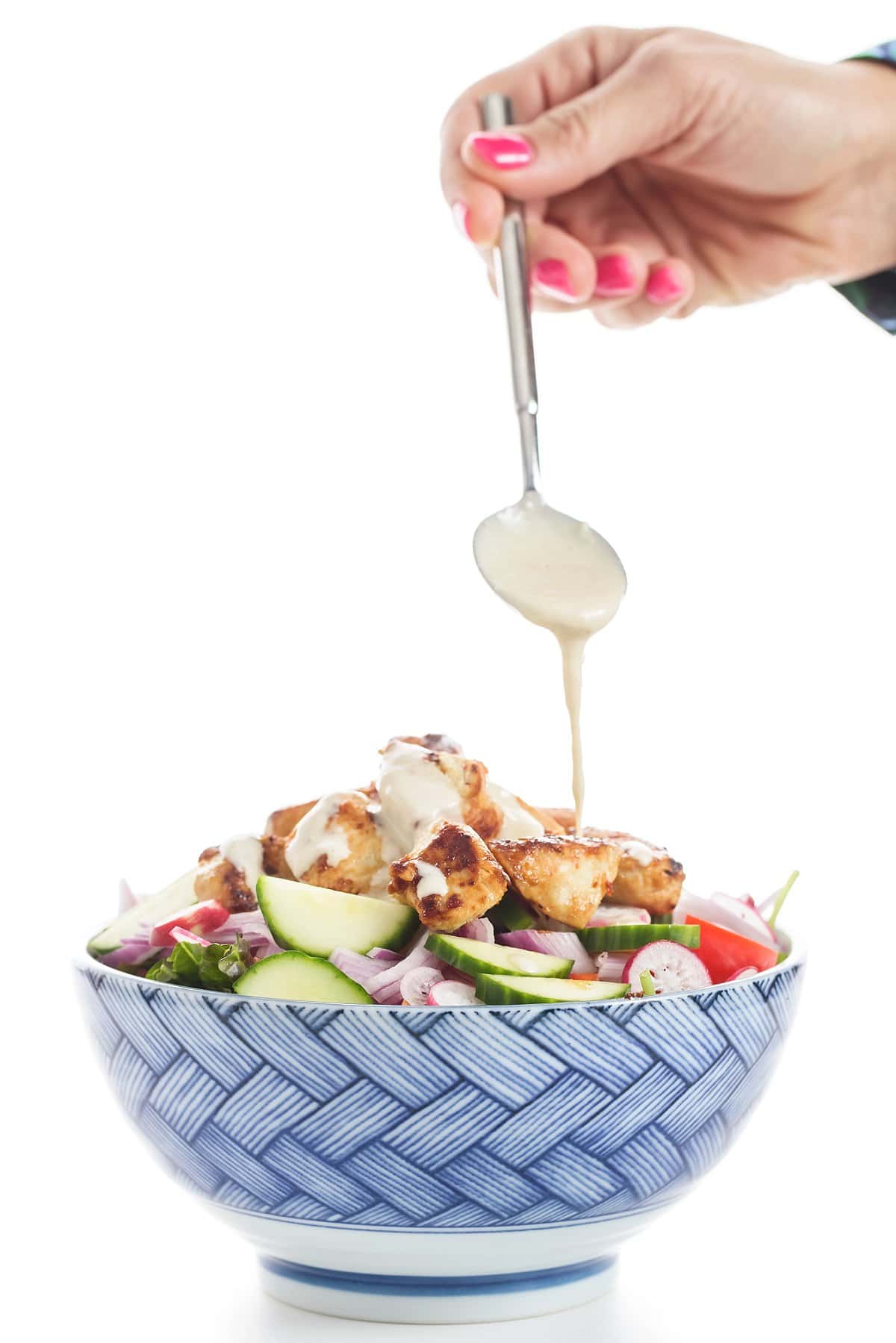 Chicken Salad with Tahini Sauce being added in a bowl