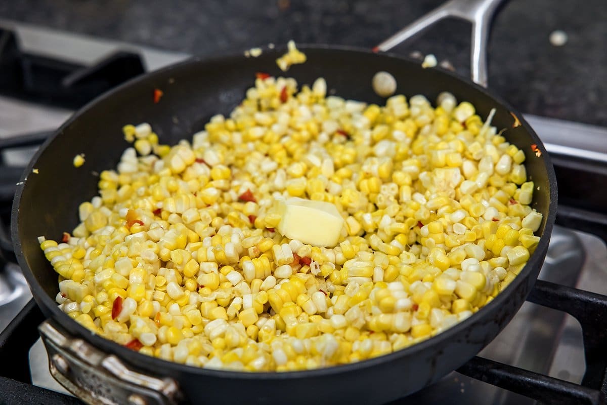 adding butter to corn skillet