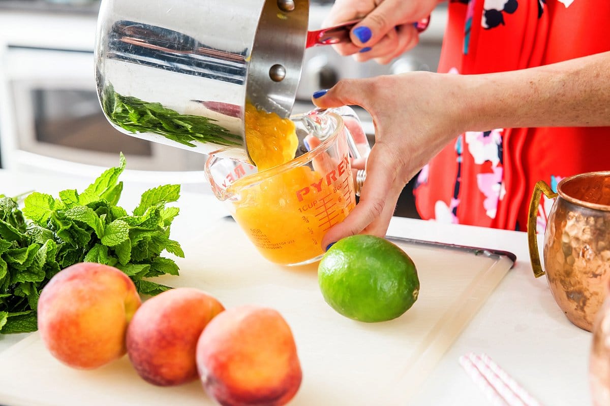 Pouring peach puree into a liquid measuring cup.