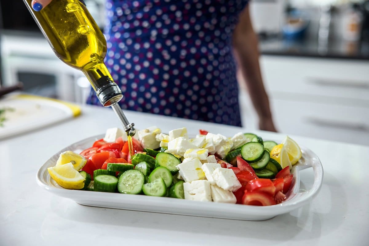 drizzling olive oil on a plate of vegetables