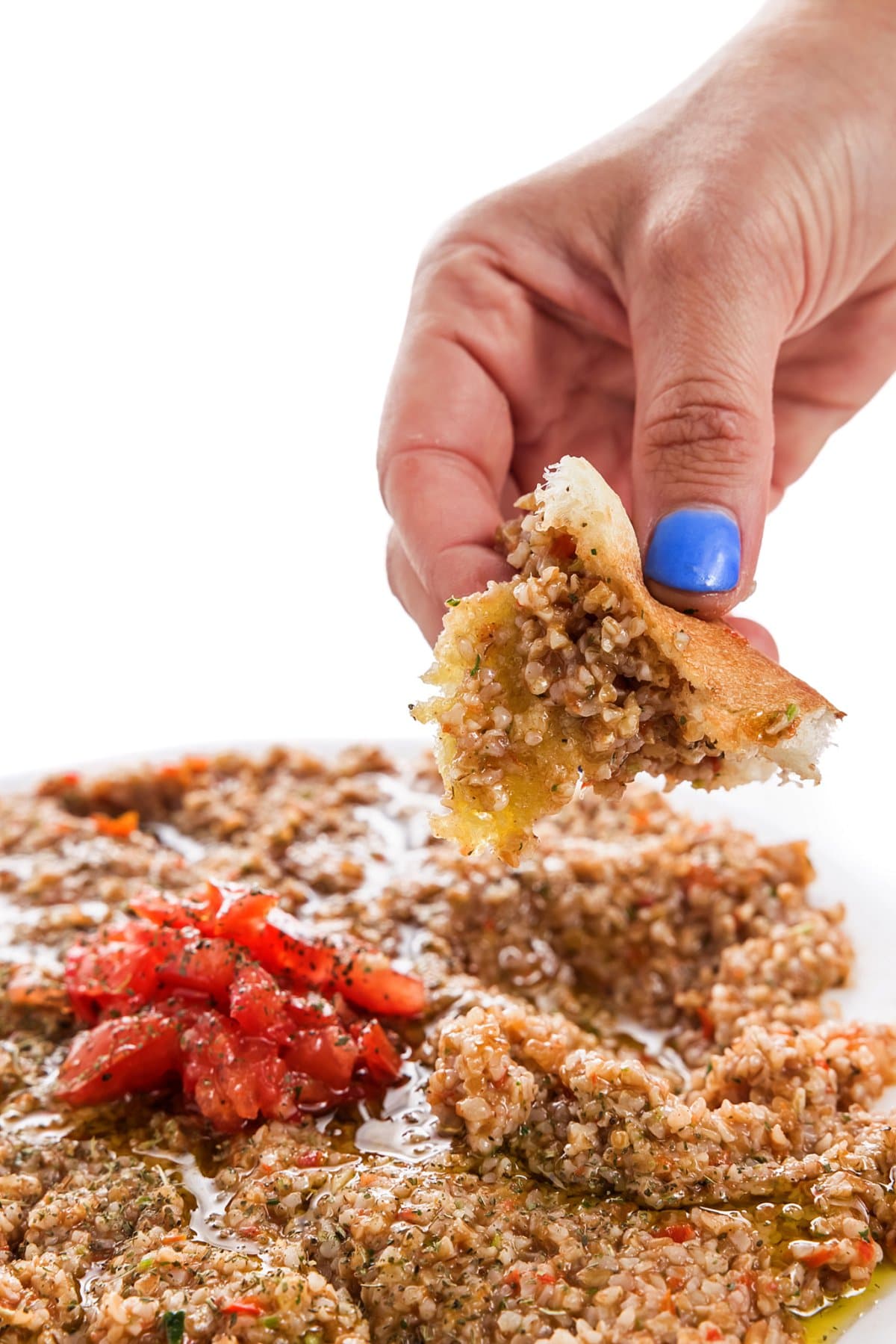 Scooping up vegan tomato kibbeh with a torn piece of pita bread.