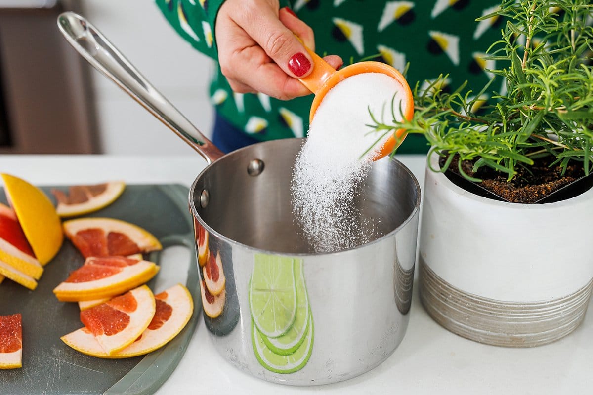 Liz adding sugar to a large sauce pan.