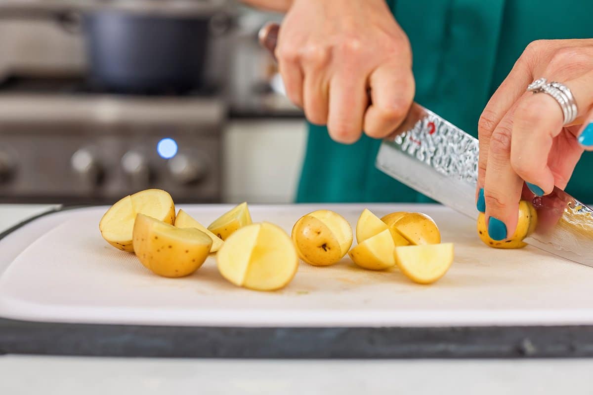 Liz cutting potatoes on a cutting board.