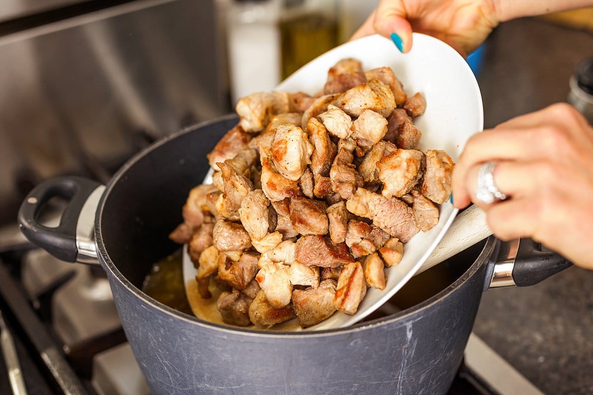 Adding cooked pork shoulder back to pot.