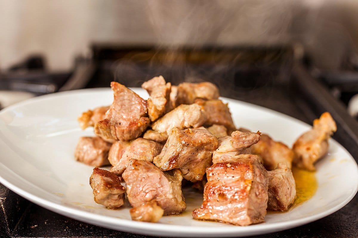 Cooked pork shoulder set aside on a plate.