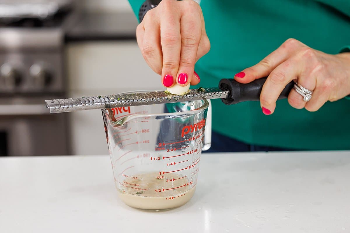 Freshly grating garlic into tahini.