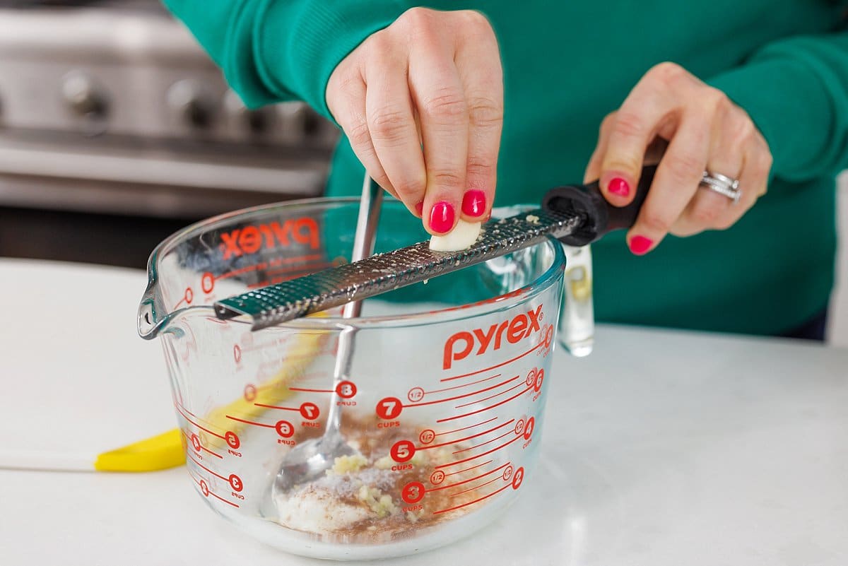 Grating garlic with a microplane into bowl.