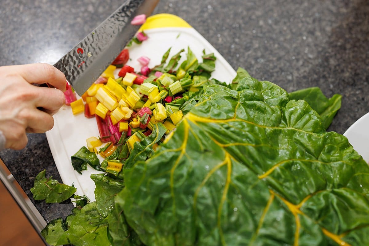 Liz cutting swiss chard on a cutting board.