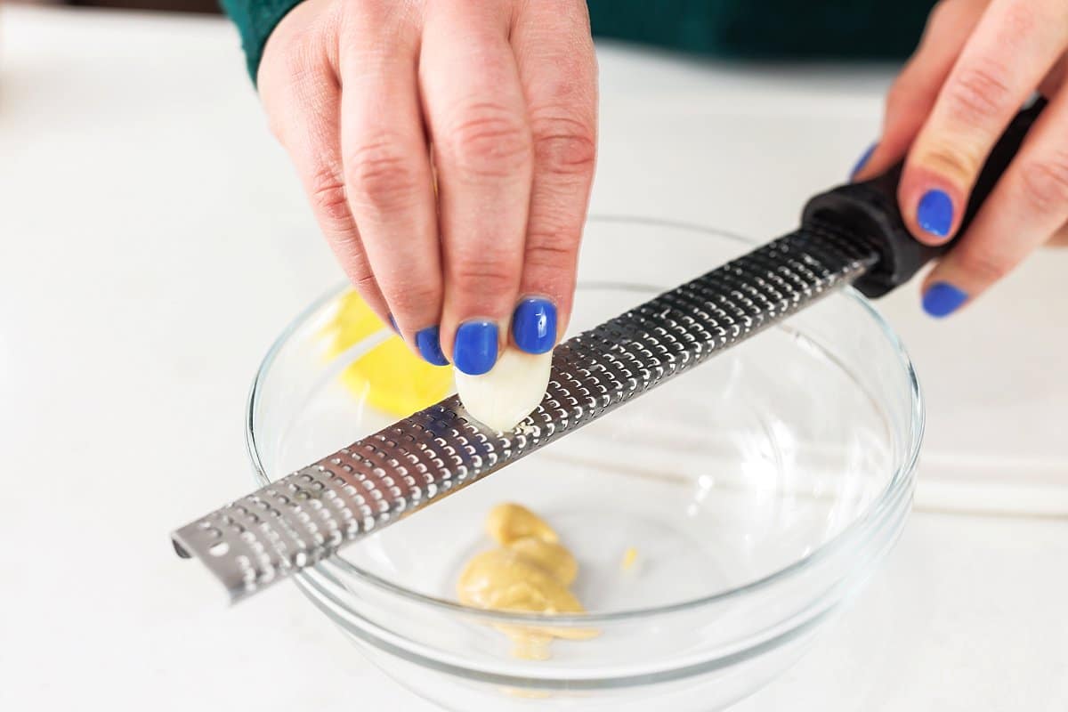 Grating garlic with a microplane into a bowl.
