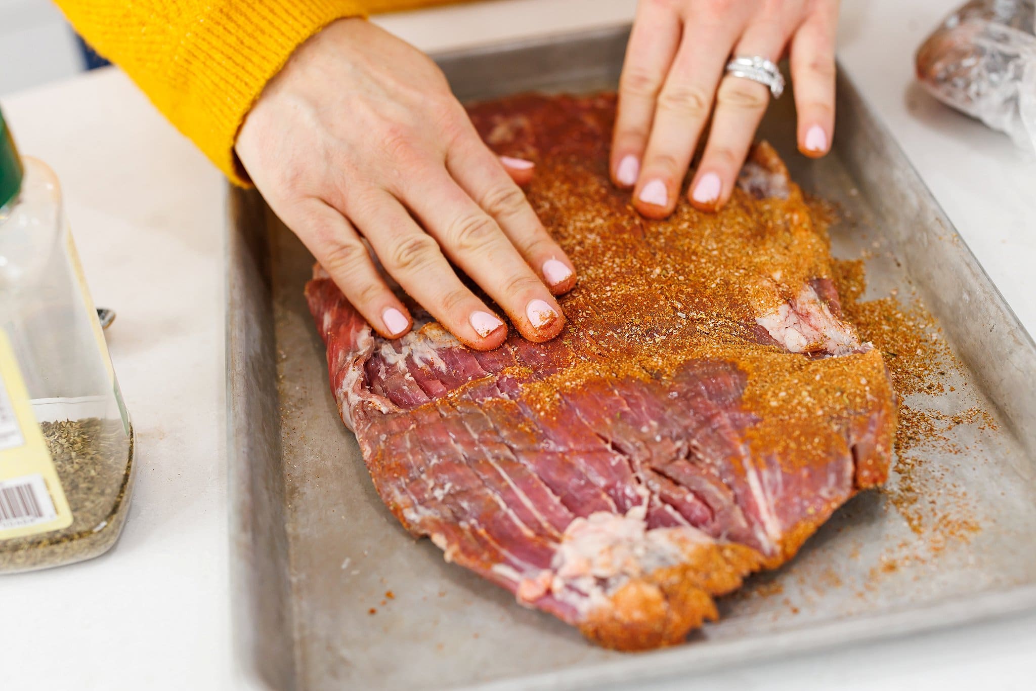 Rubbing dry rub spices over flank steak.
