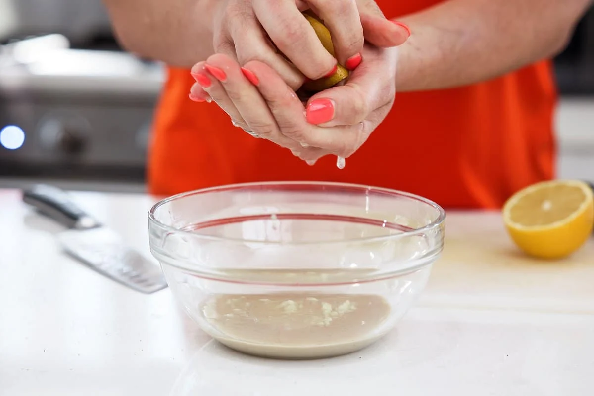 Squeezing lemon juice into tahini.