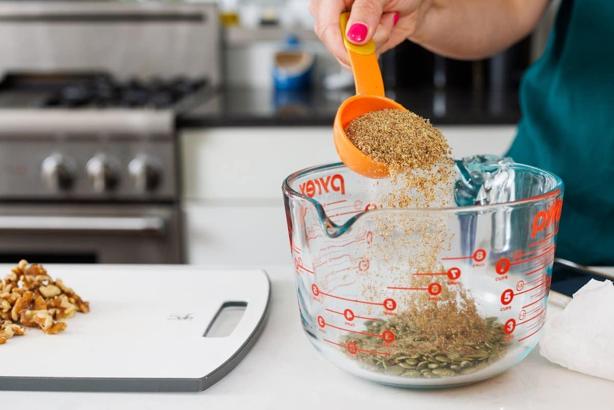 Adding flax seed meal to bowl of pumpkin seeds.