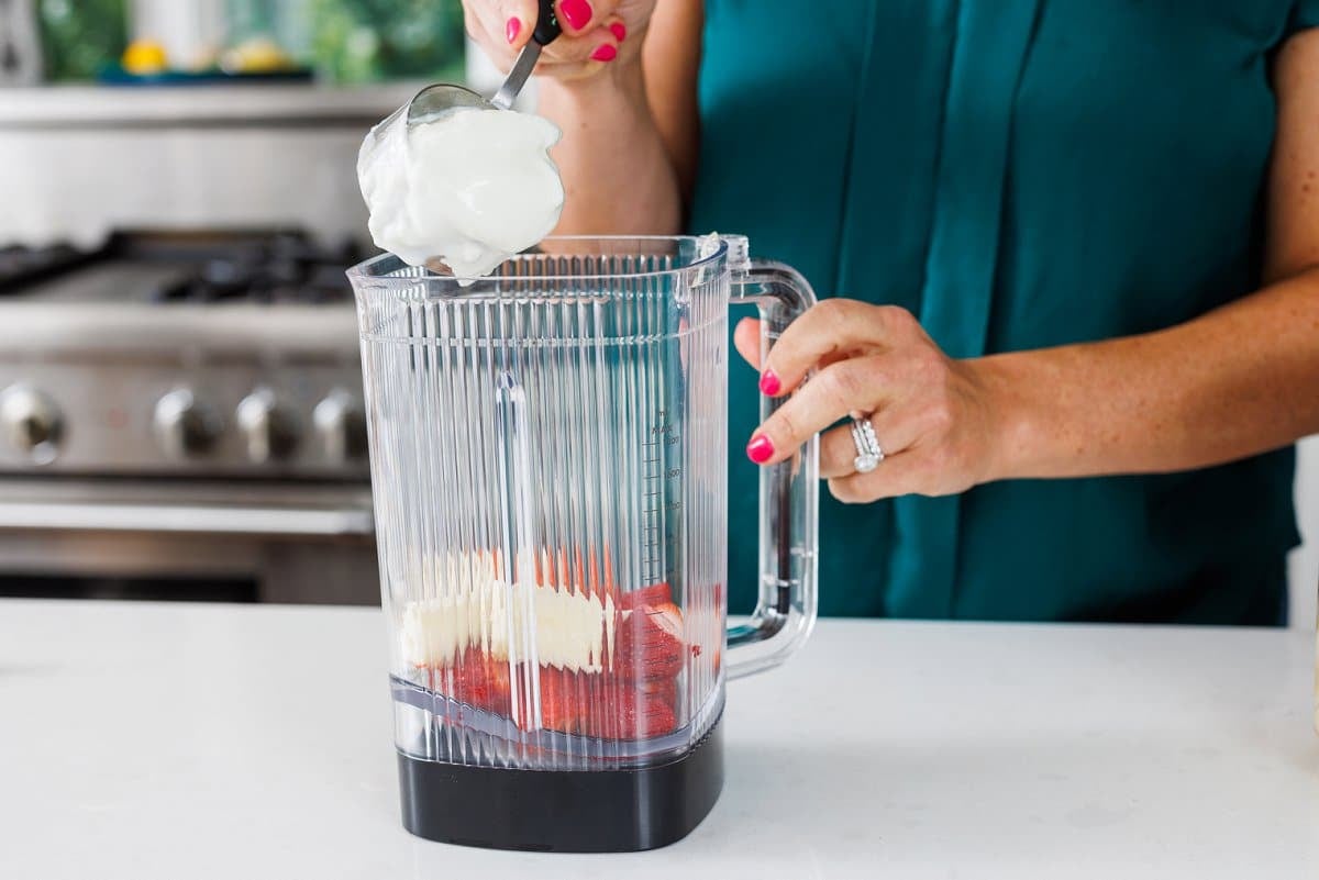 Liz adding yogurt to the blender for a smoothie.