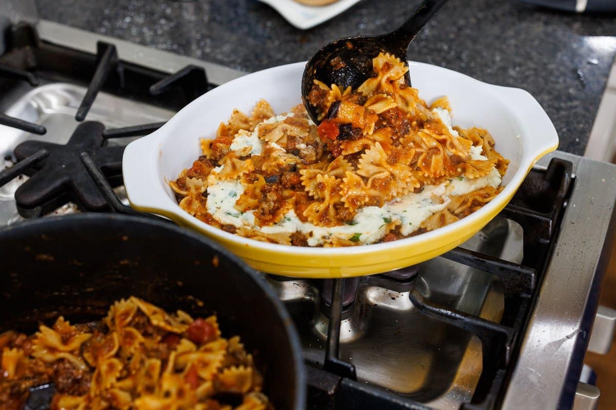 Layering cooked pasta and ricotta cheese mix in casserole dish.