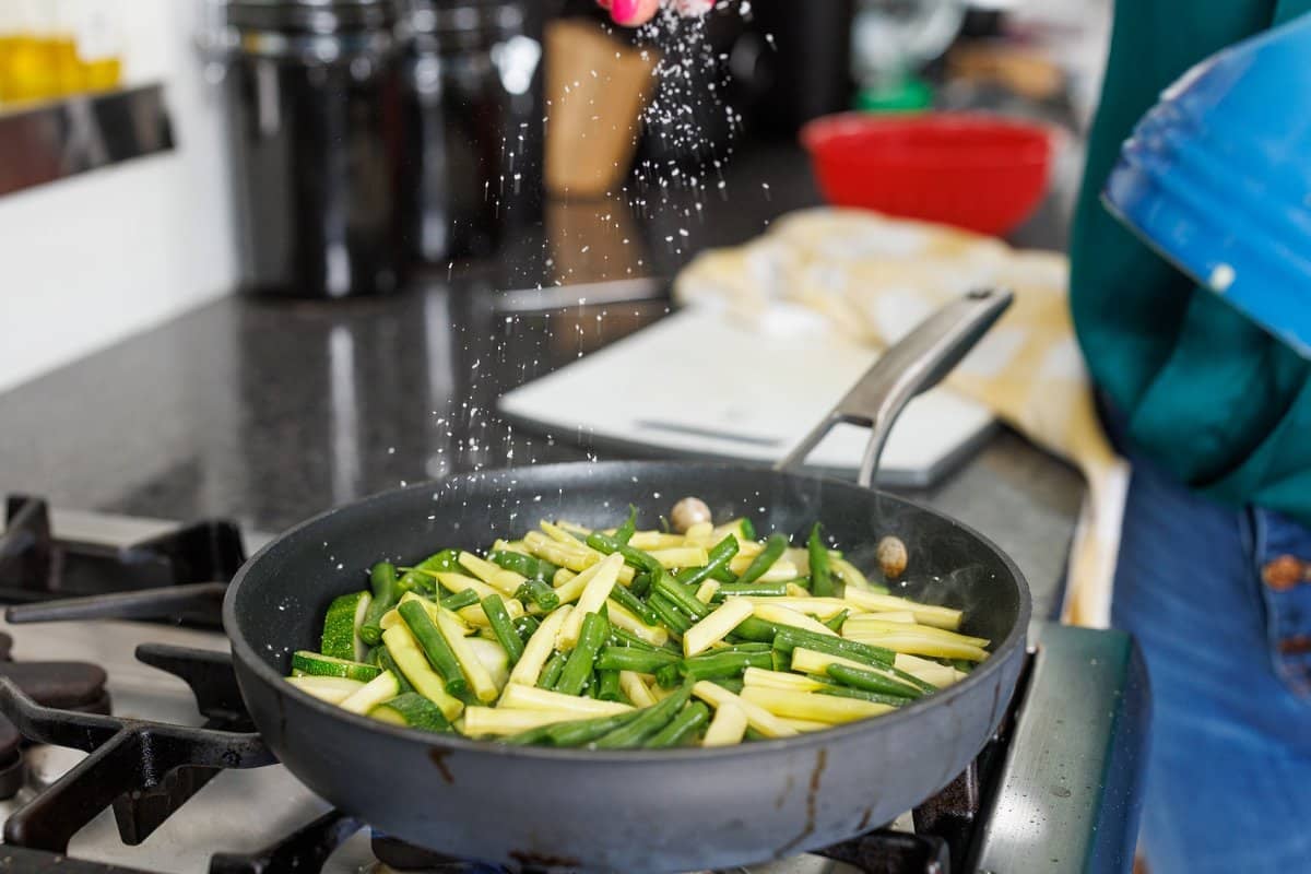 Sprinkling green beans in pan with salt.