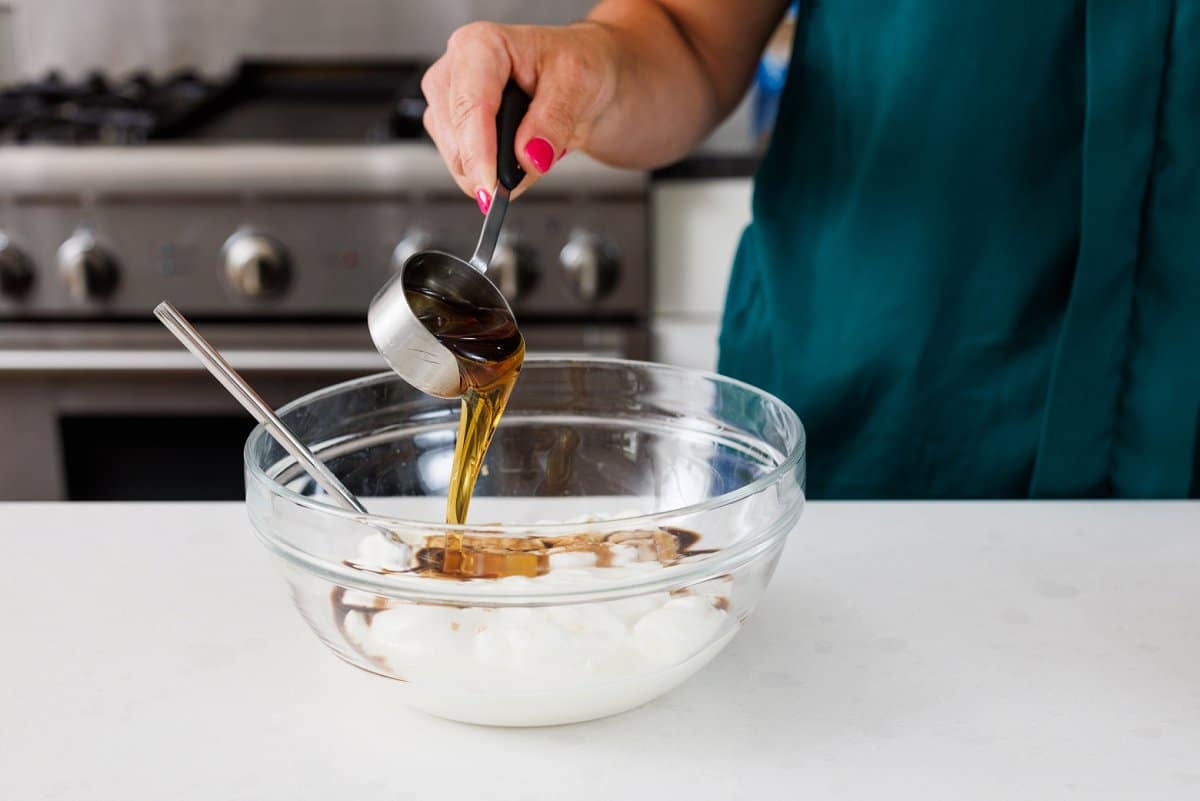 Adding maple syrup to bowl of yogurt.