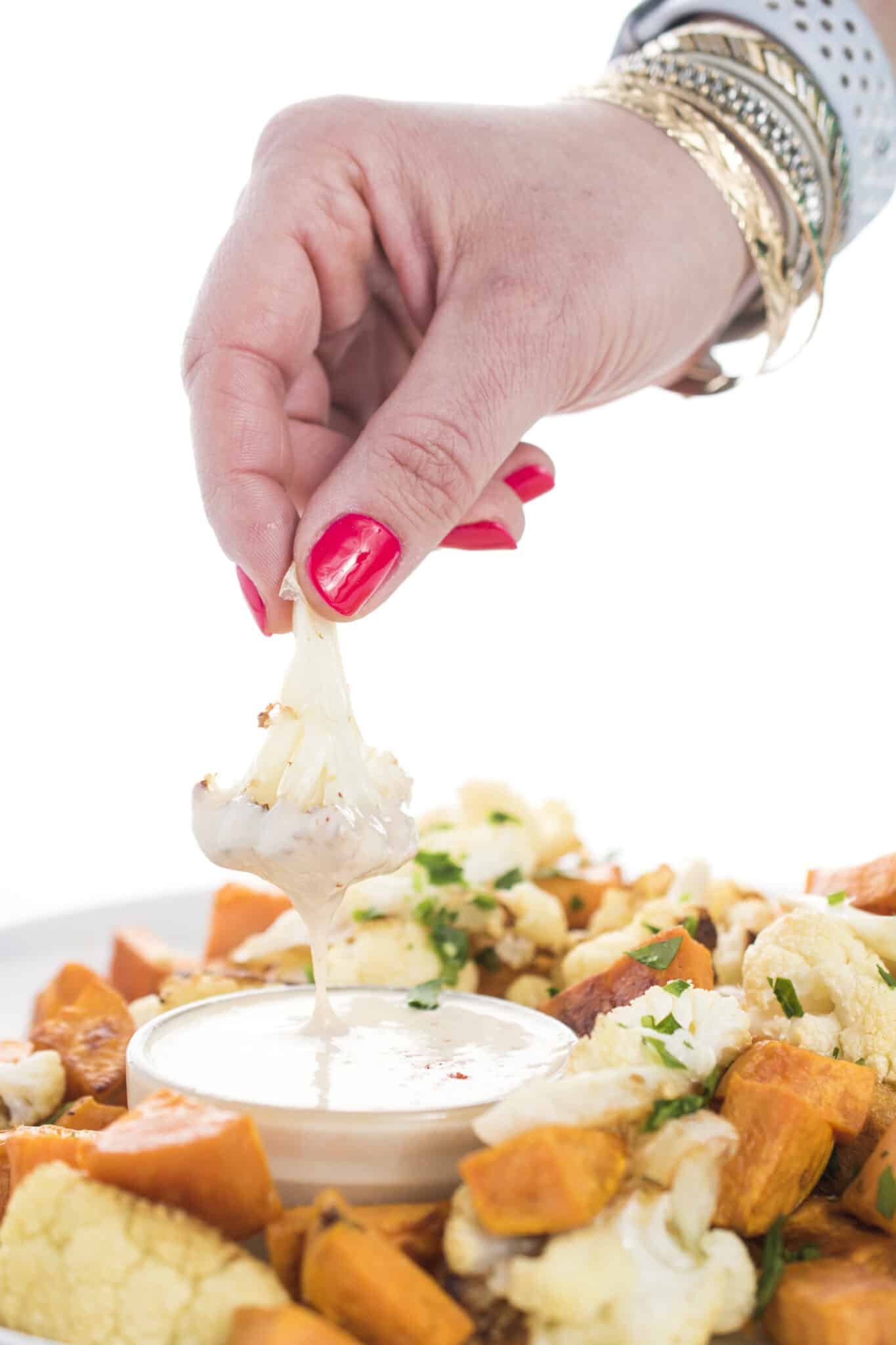 Dipping roasted vegetables in tahini lemon sauce.