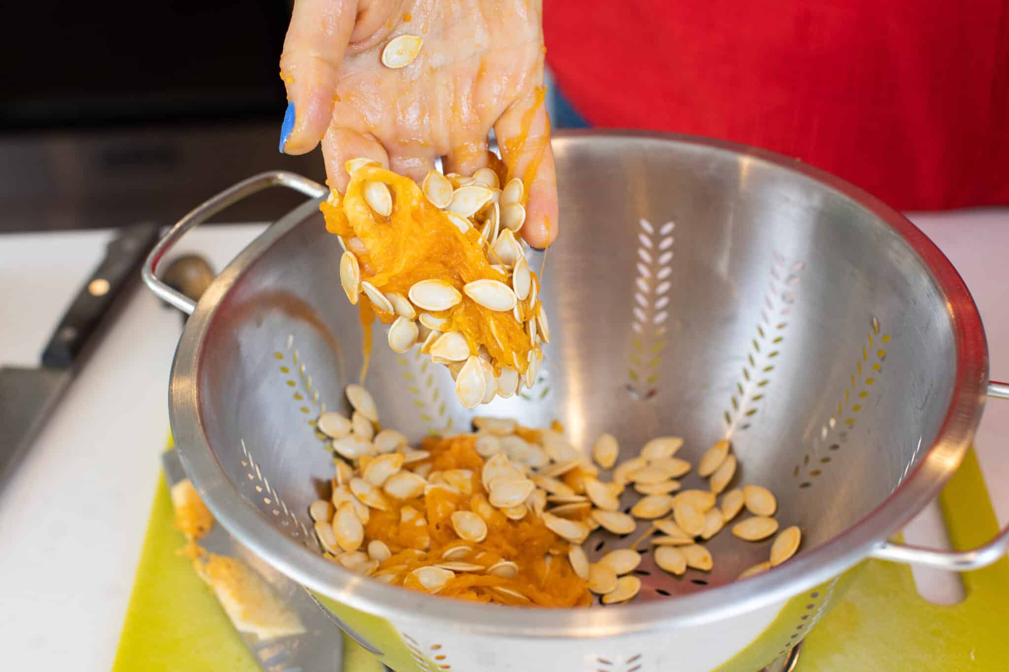 Putting dirty pumpkin seeds in a colander.
