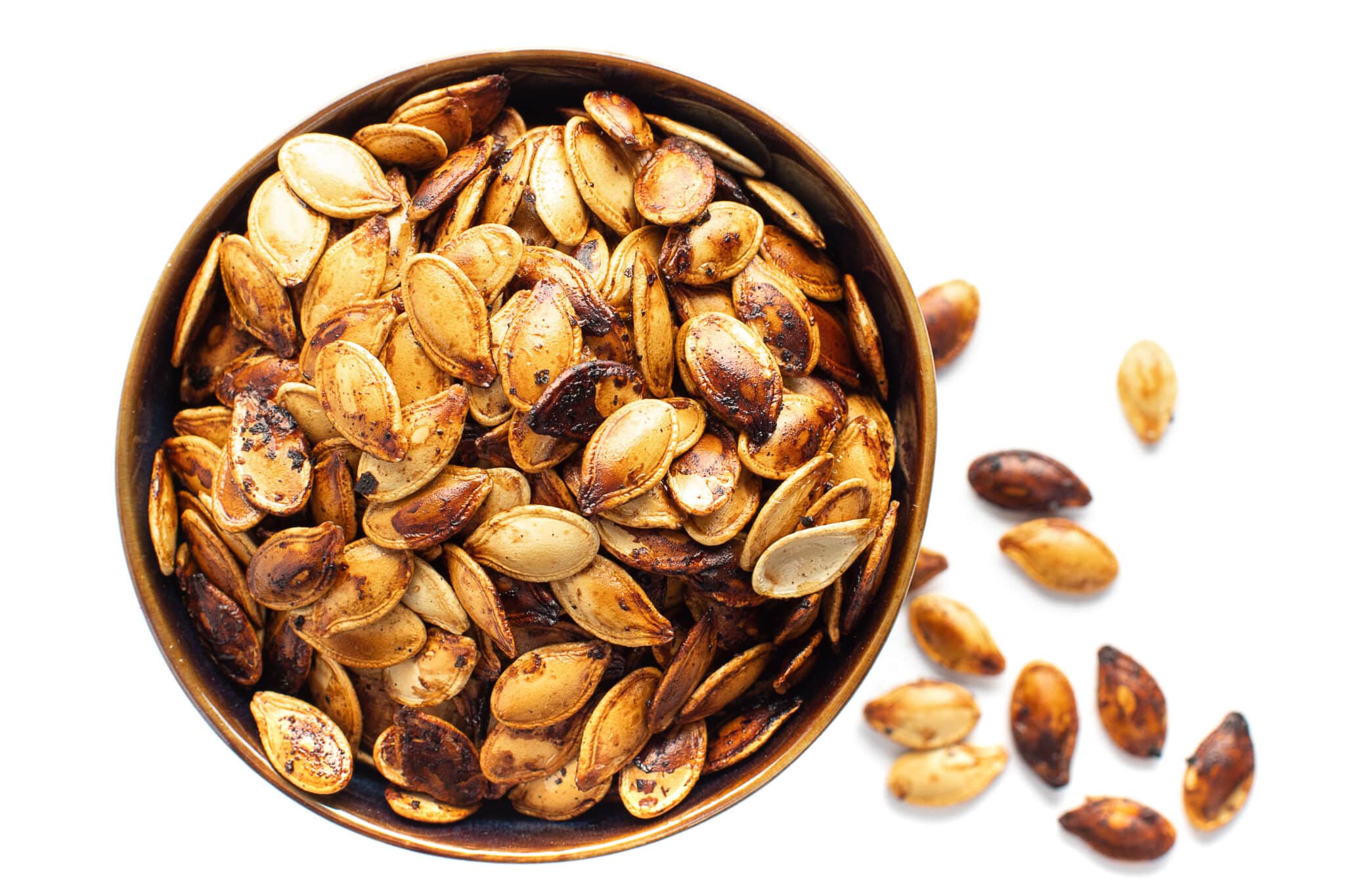 Roasted and seasoned pumpkin seeds in a bowl.