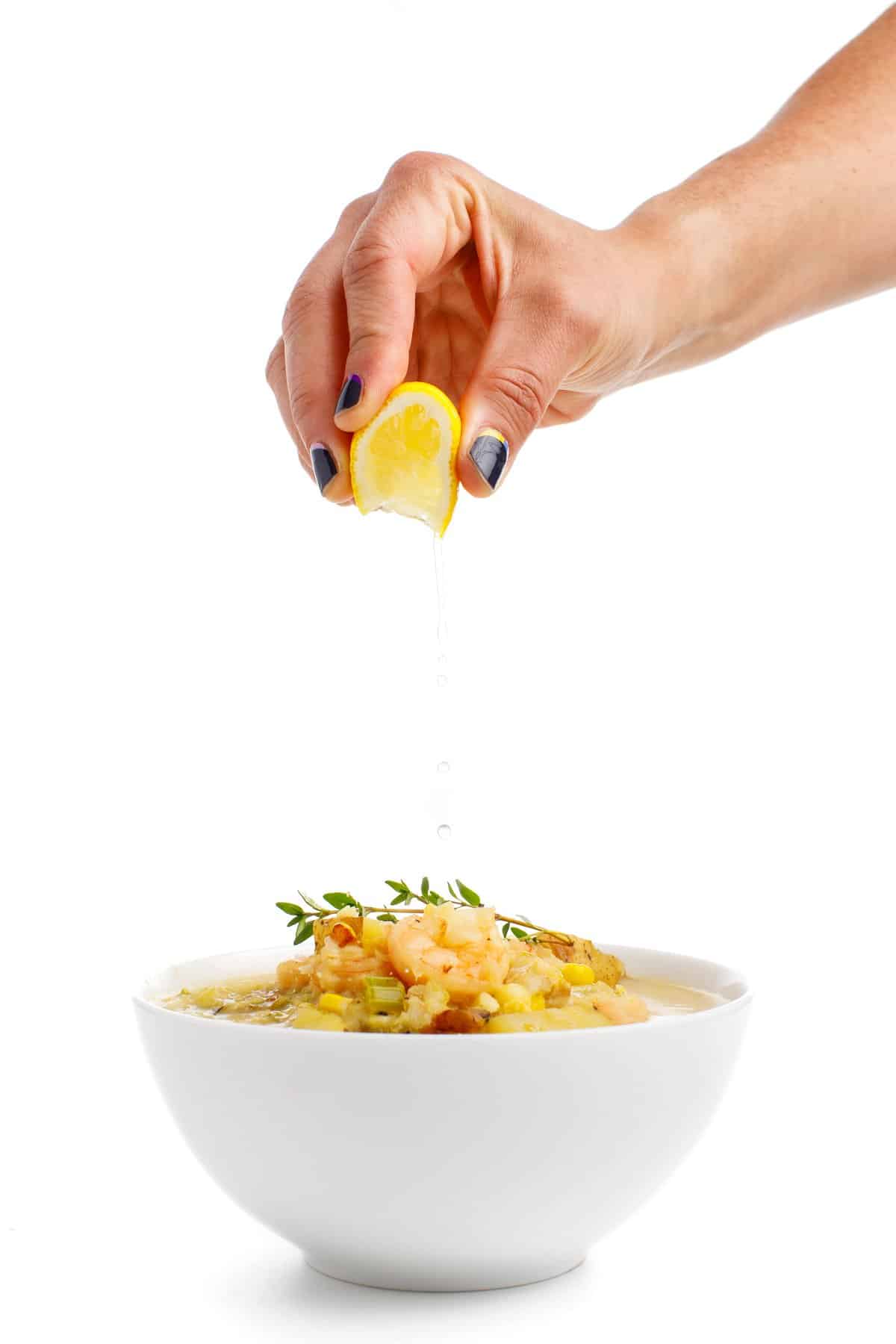 Garnishing lightened seafood chowder with lemon juice.