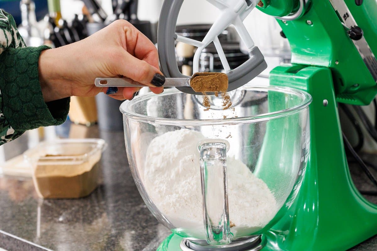 Adding cinnamon to a mixing bowl of flour.