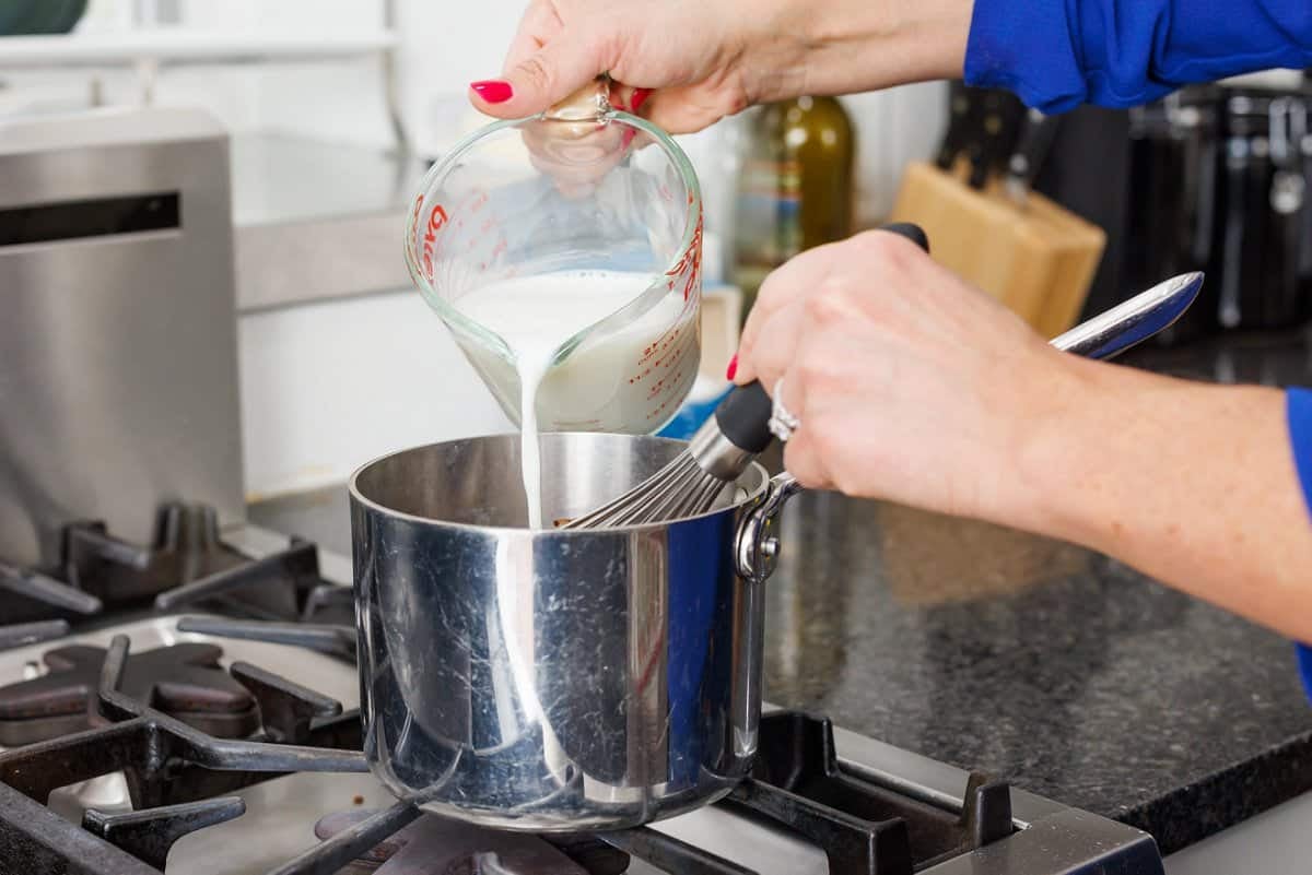 Pouring milk into sauce pan and whisking hot cocoa.
