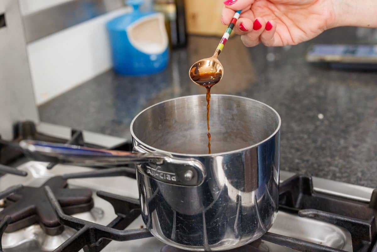 Adding vanilla extract to sauce pan on stove.