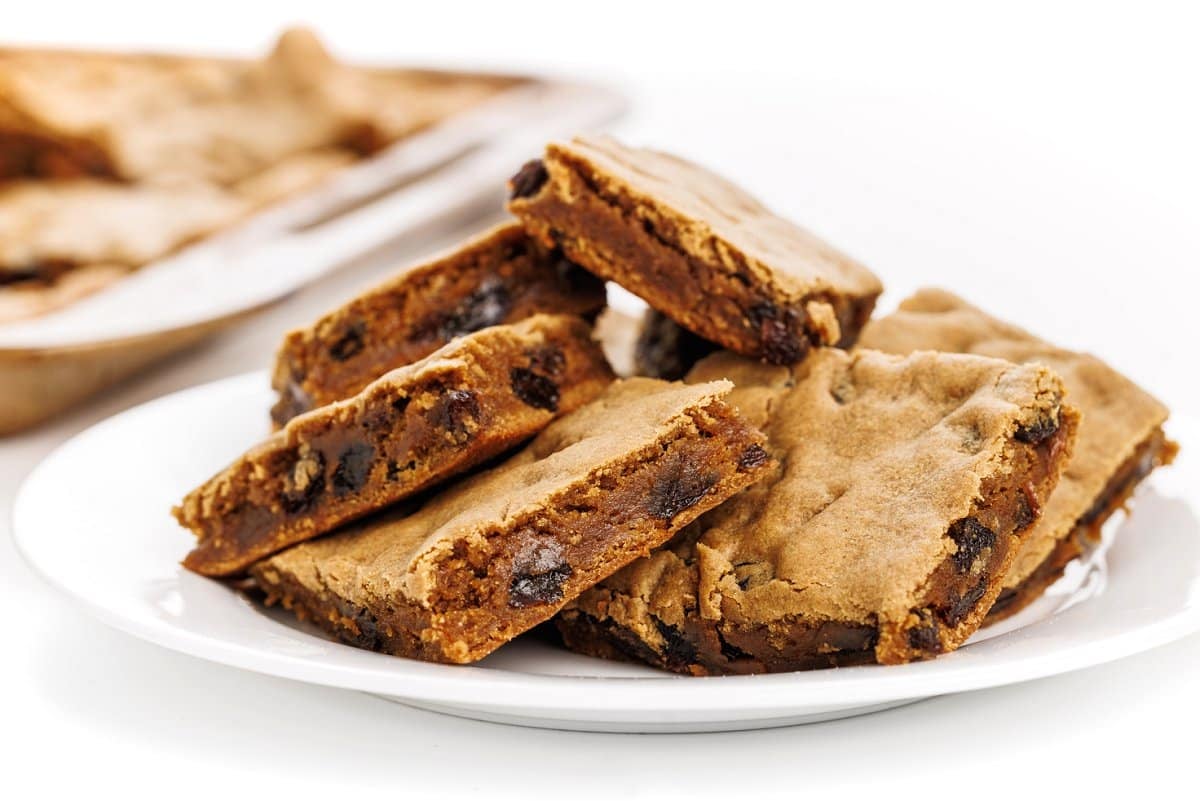 New England hermit cookie bars cut into squares on a plate, with the rest of the tray in the background.