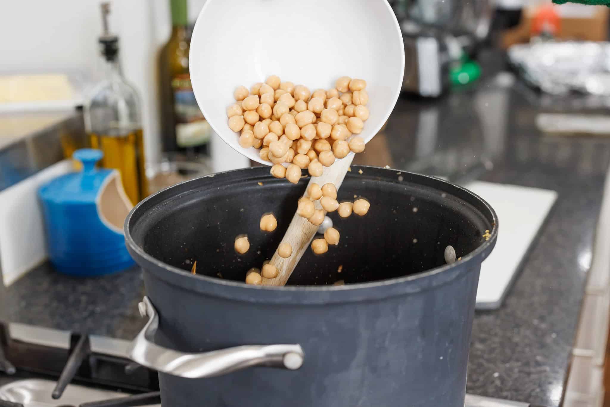 Adding drained chickpeas to pot.