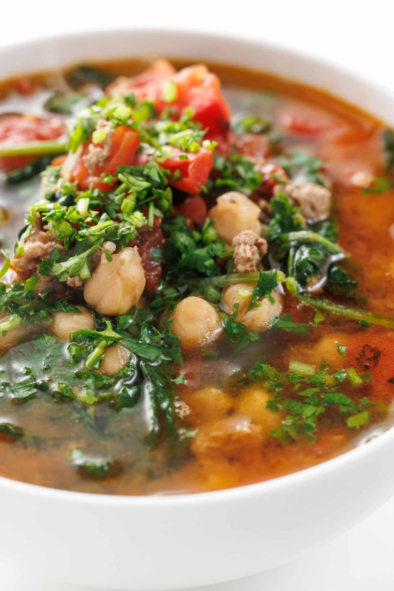 Close up of lamb and chickpea stew with spinach garnished with fresh parsley.