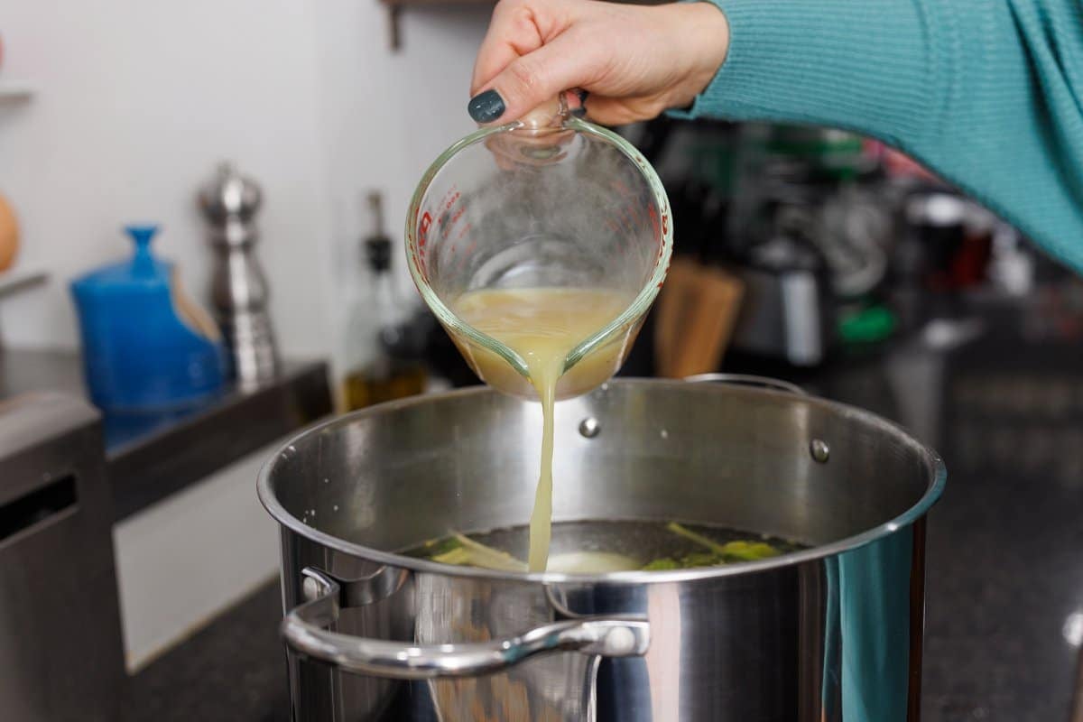 Pouring chicken base into stock pot.