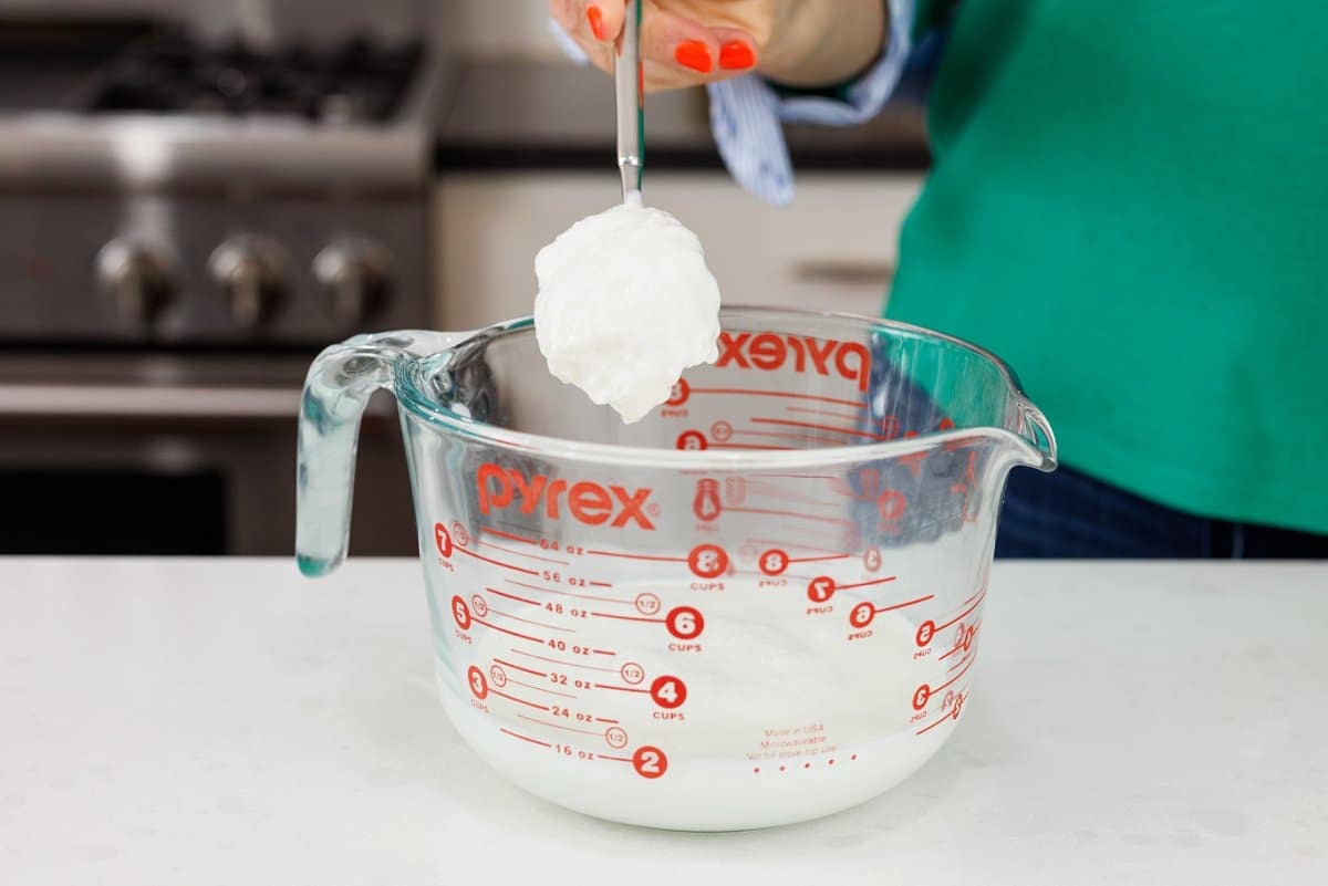 Adding yogurt to a large mixing bowl.