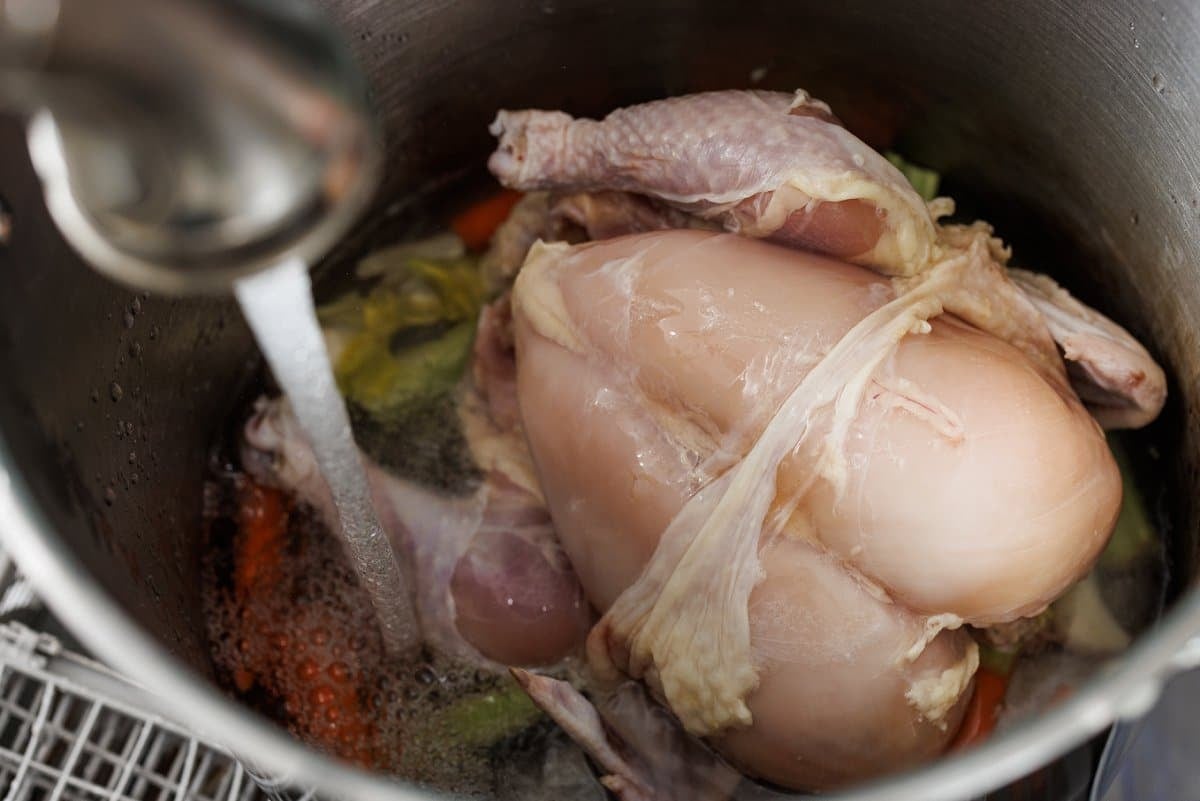 Making chicken stock in a large pot with a whole chicken.