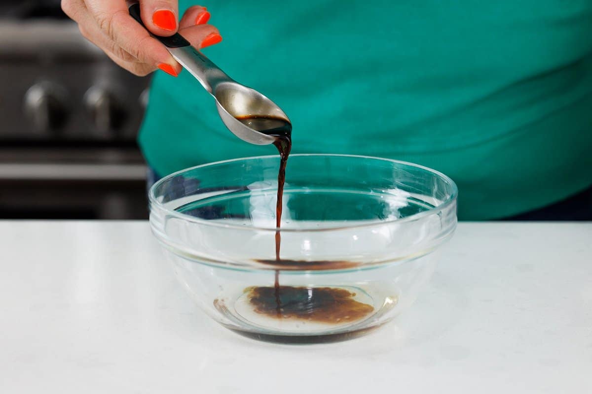 Adding soy sauce to glass bowl.