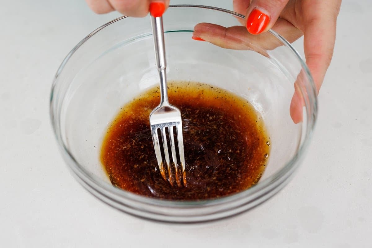 Whisking ginger salad dressing together with a fork.