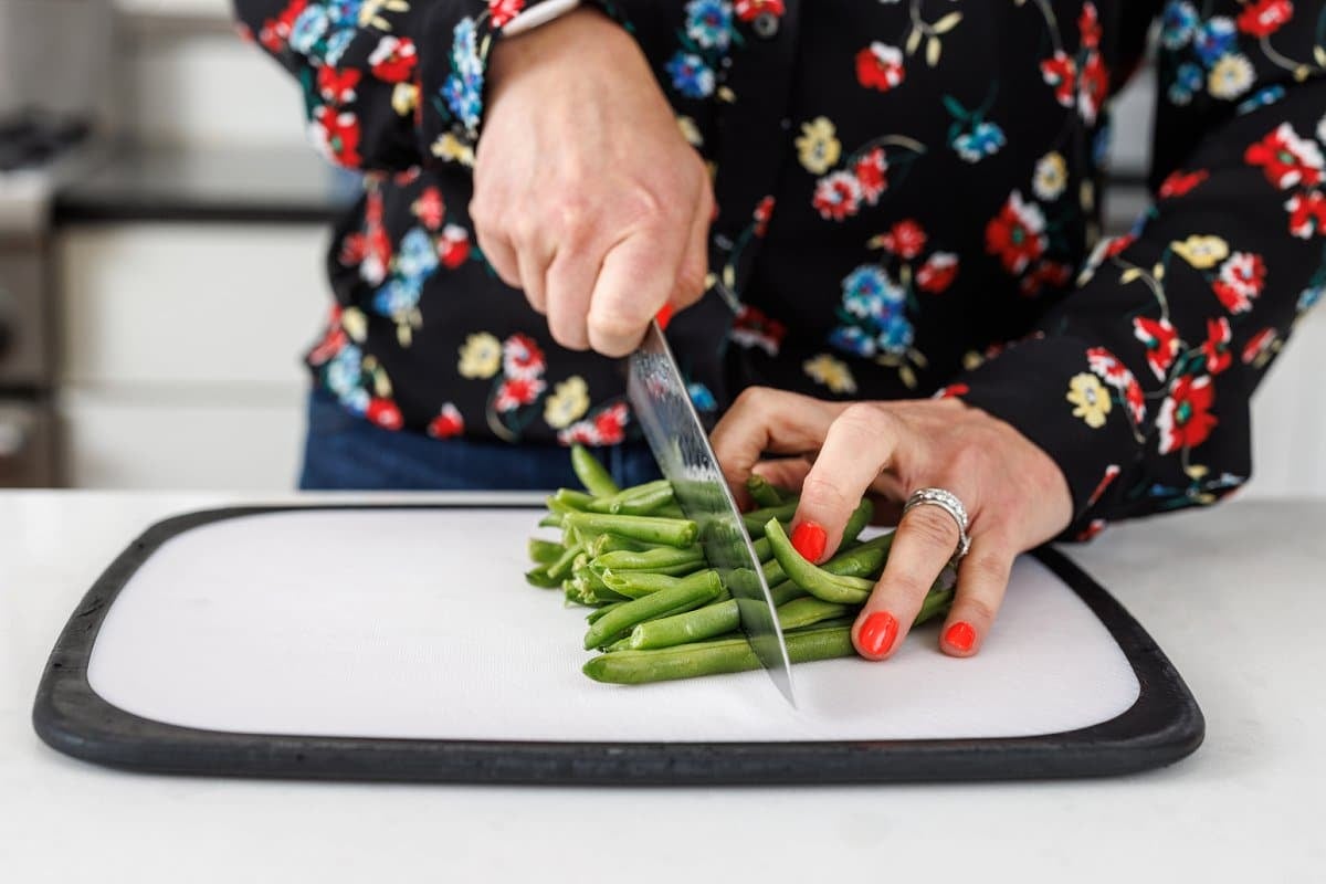 Liz trimming fresh green beans on a cutting board.