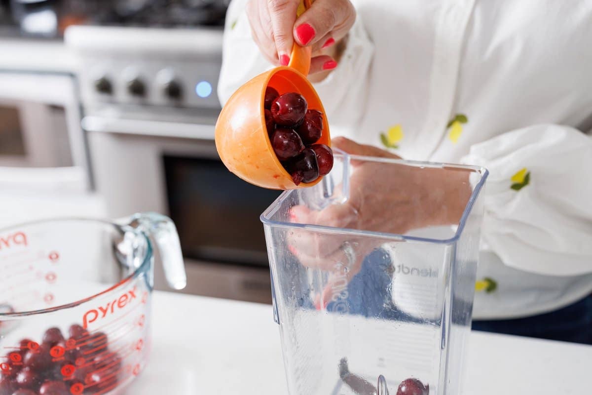Adding cherries to blender for smoothie.