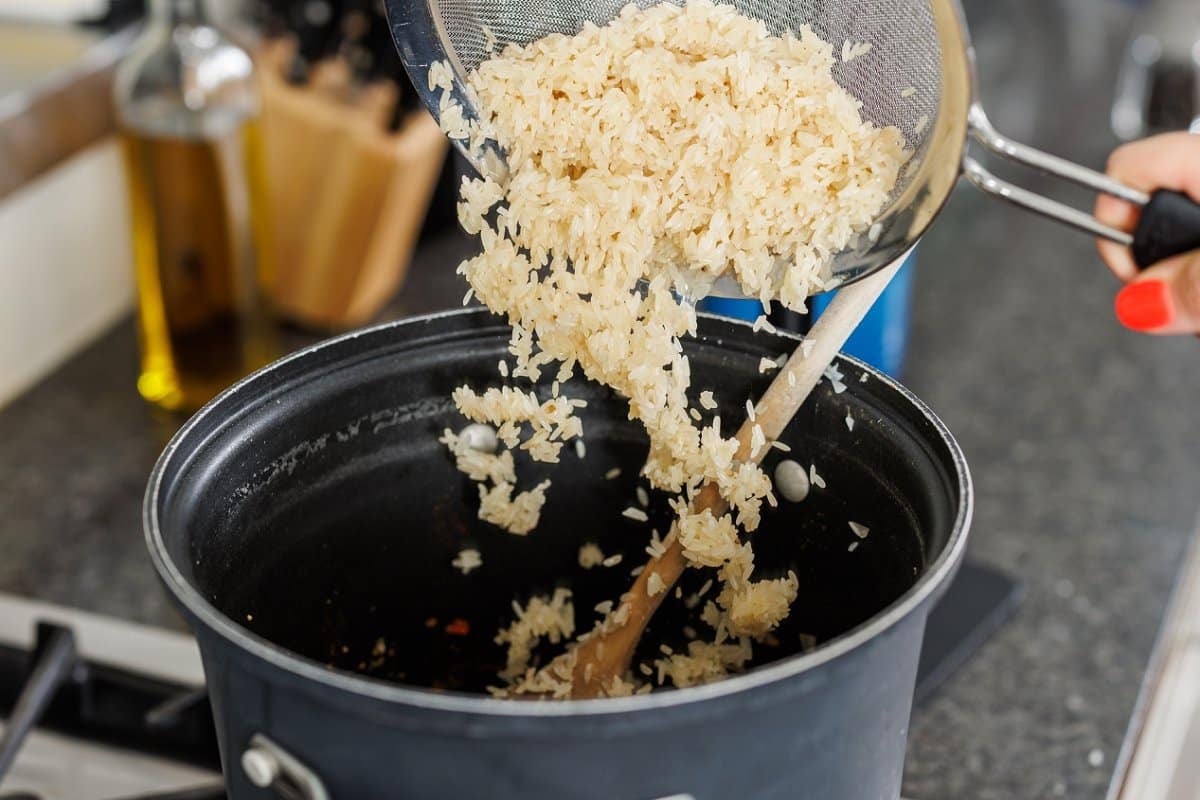 Adding white rice to large pot.