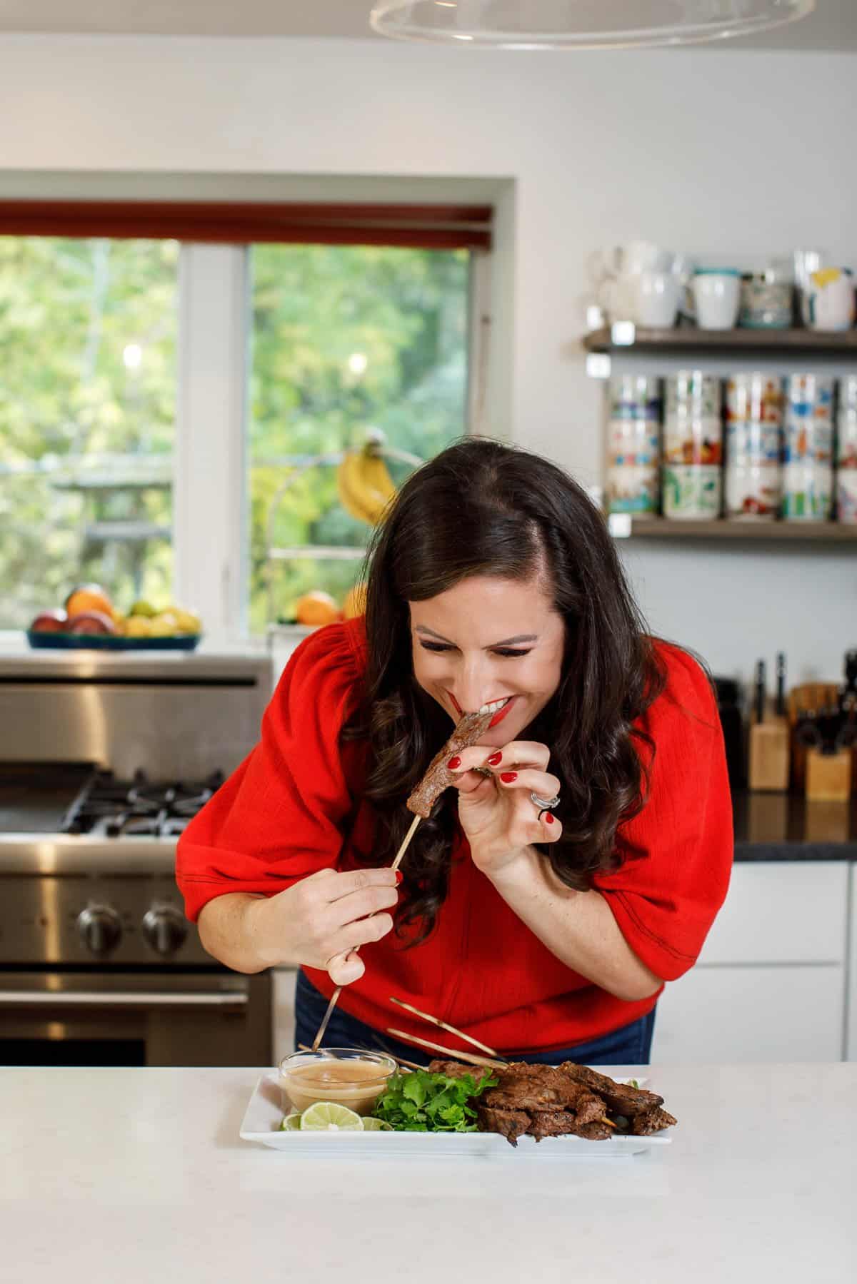 Liz eating beef satay skewers with peanut dipping sauce.